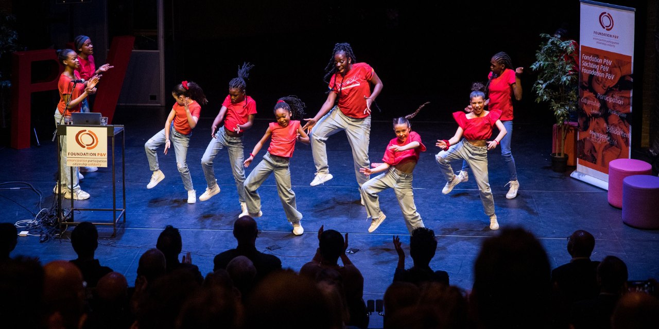 Een groep jongeren voert een dans uit op een podium